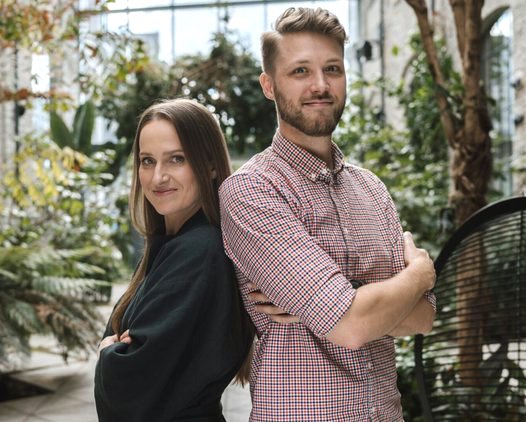 Two of the Yaga team standing back to back in a greenhouse